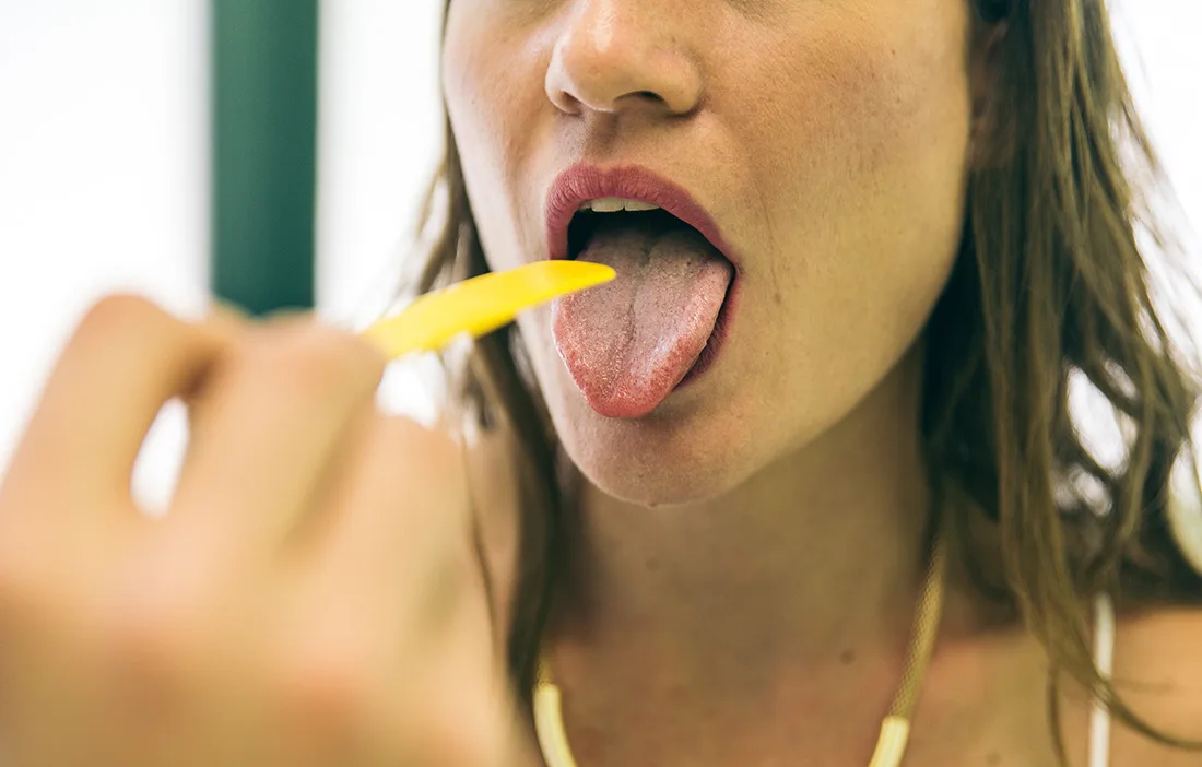 Woman sticking out her tongue while checking her mouth
