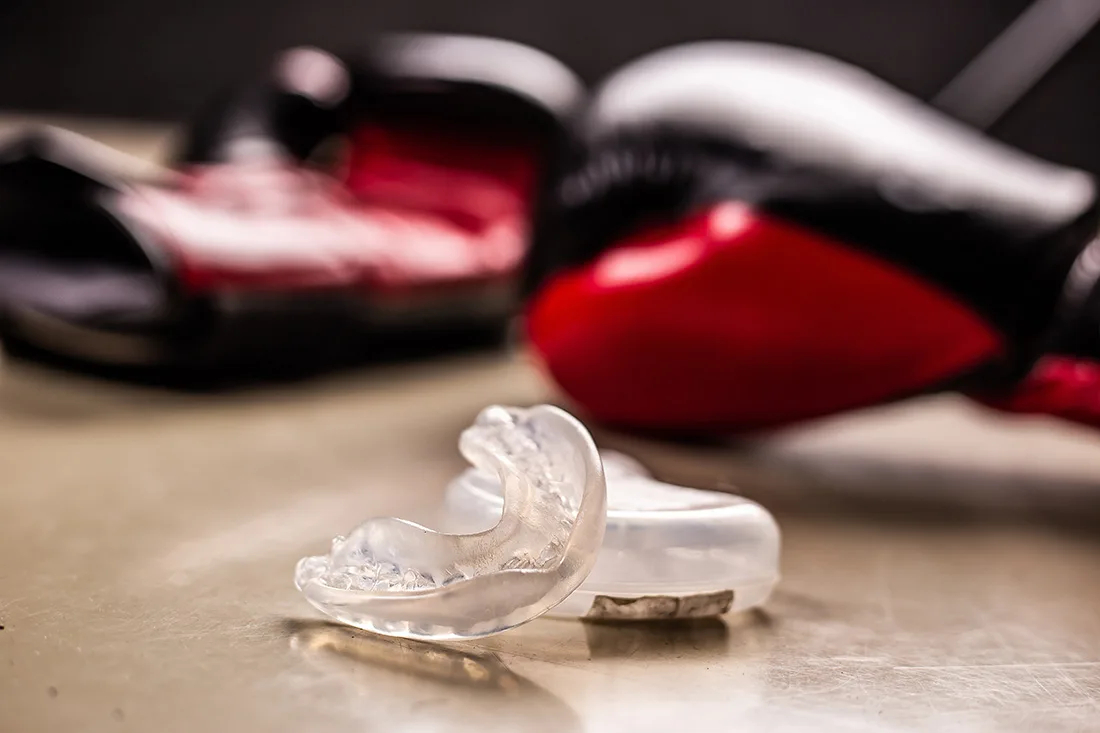 Clear mouthguard resting on a table in front of boxing gloves