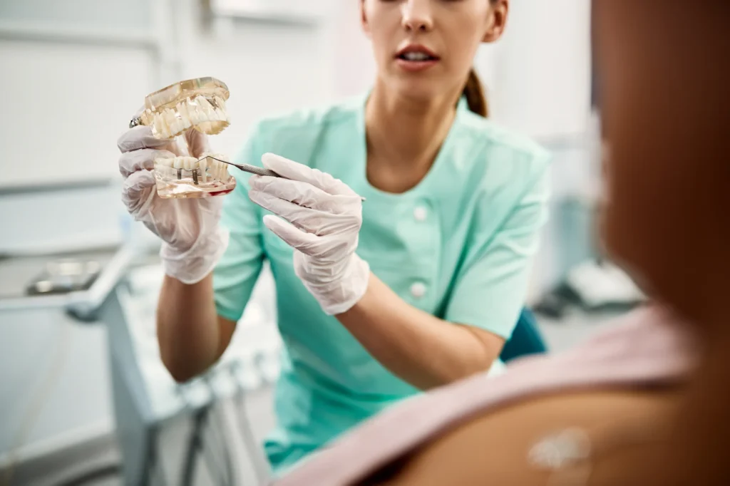 Dentist explaining single tooth implant and full mouth dental implant options to a patient at Designing Smiles